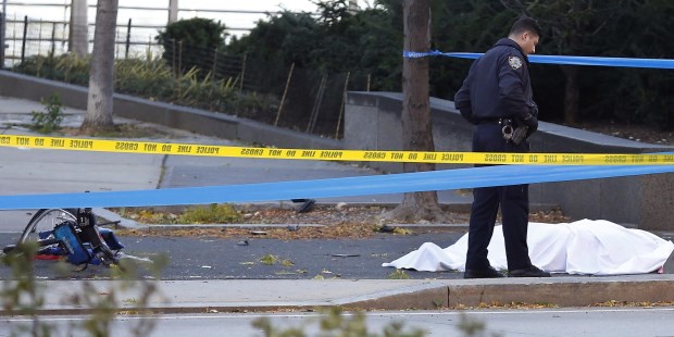 Autoridades investigan en la escena del crimen, junto a un cuerpo cubierto con una sábana blanca y una bicicleta destruida.