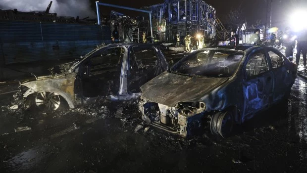 Los trabajadores de rescate caminan frente a un automóvil y un edificio destruido por un ataque ruso en Zaporizhzhia, Ucrania (6-12-2024).